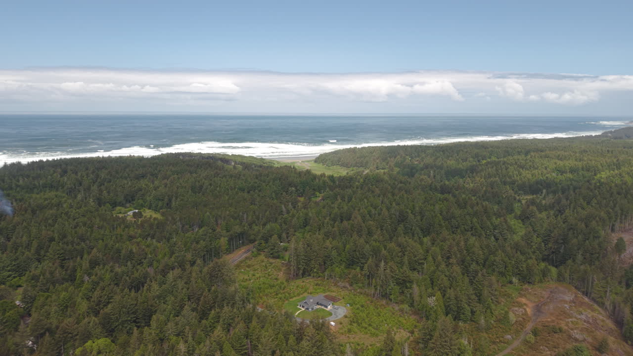 Bandon Oregon, rural landscape with scattered homes in forest. Aerial panning shot with ocean background.
