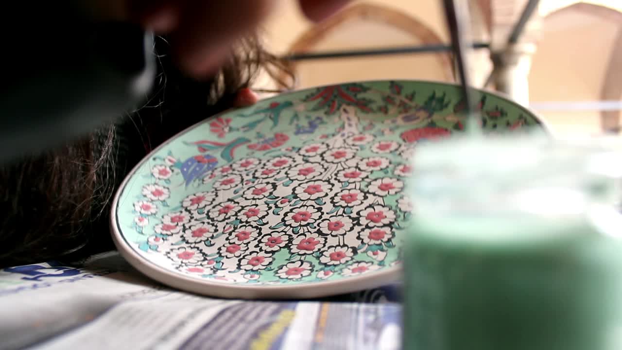 artista pintando motivos tradicionales de porcelana de azulejos otomanos
