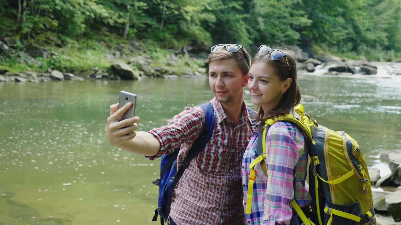 un hombre con una novia es fotografiado contra el fondo de un río de montaña en un día nublado