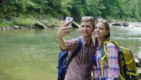 a man with a girlfriend are photographed against the background of a mountain river on a cloudy day