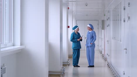 Two-women-talking-in-white-corridor.-Factory-women-conversation