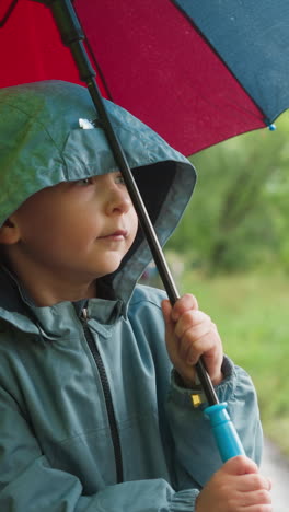 kid shelters beneath umbrella in park. focused boy finds solace under cover from spring rain embracing healthy pursuit of walking among tranquil setting