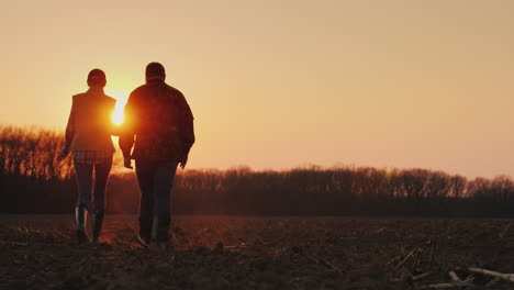 Dos-Granjeros,-Un-Hombre-Y-Una-Mujer-Caminando-Por-Un-Campo-Arado-Hablando