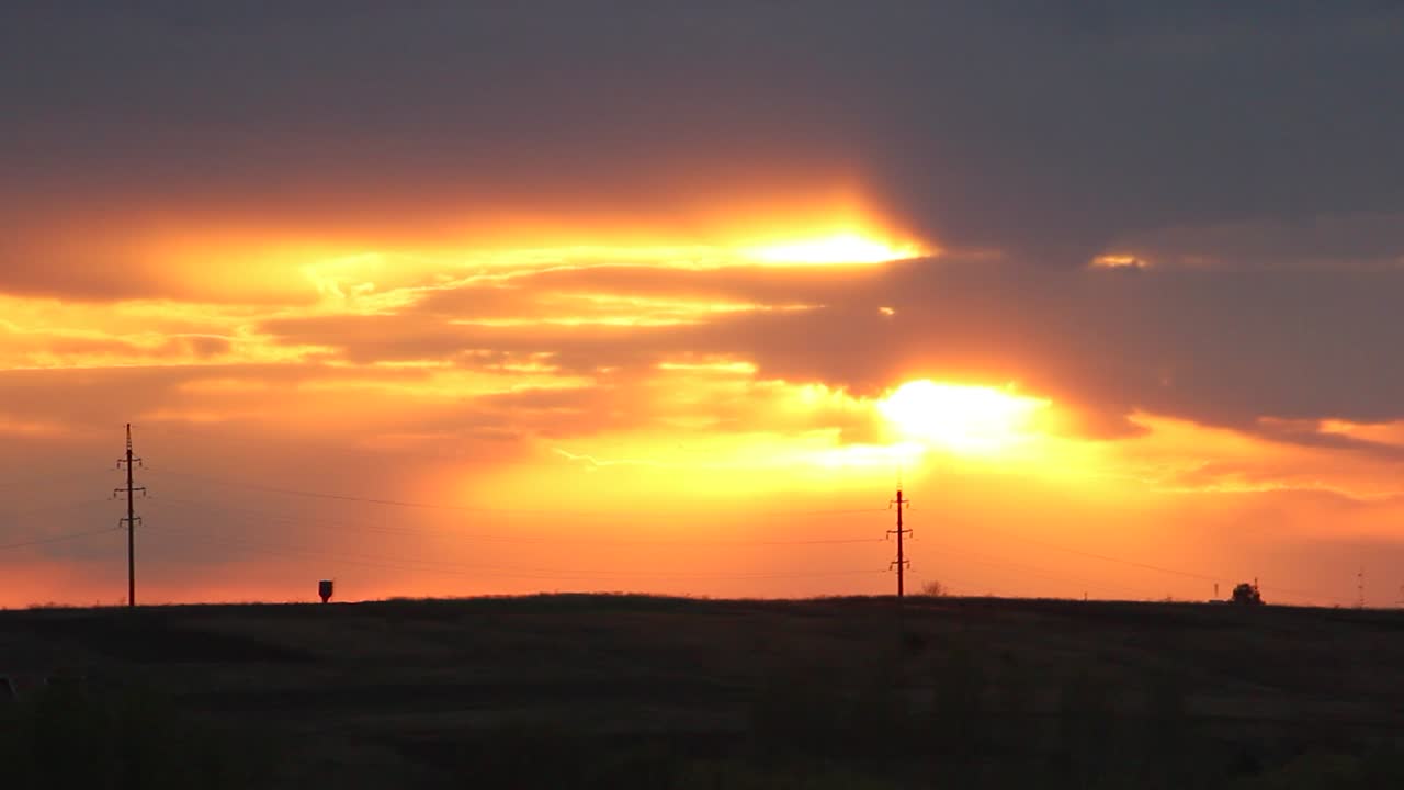 Sun slowly go down over the green field's near small village. Clouds passing by covering the sunset!