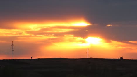 sun slowly go down over the green field's near small village. clouds passing by covering the sunset!