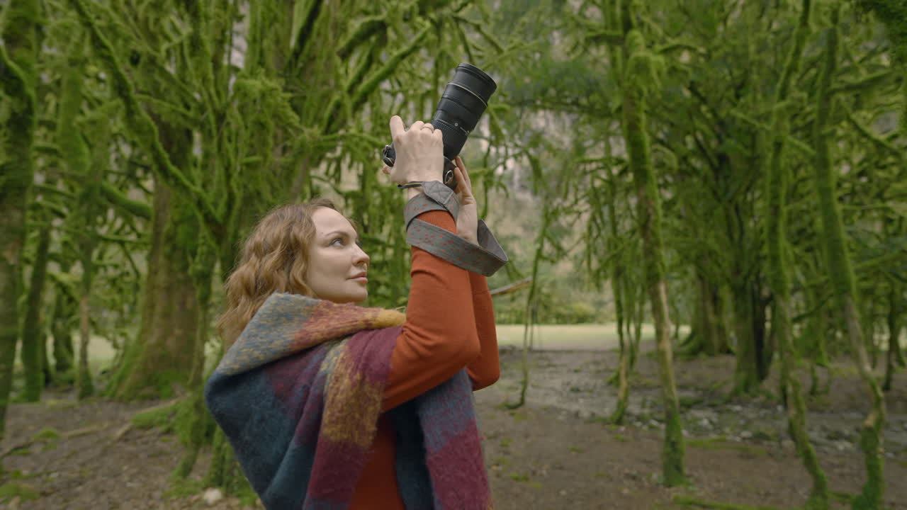 женщина фотографирует в лесу, покрытом мохом.