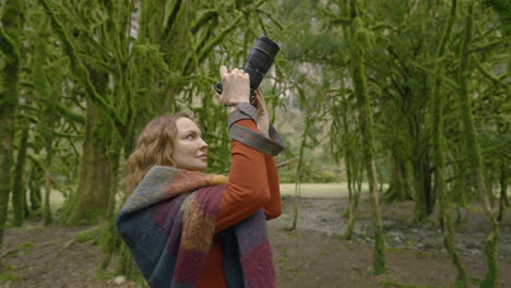 mujer tomando fotos en un bosque cubierto de musgo