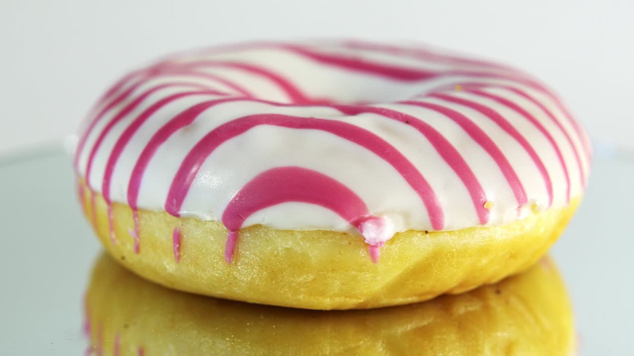 rosquillas giratorias con diferentes rellenos en la mesa del espejo. deliciosa rosquilla dulce girando en un plato. rosquilla brillante y colorida macro disparo de primer plano girando sobre un fondo blanco. bucle sin costuras.