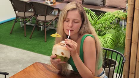 woman enjoying a coconut drink at a cafe