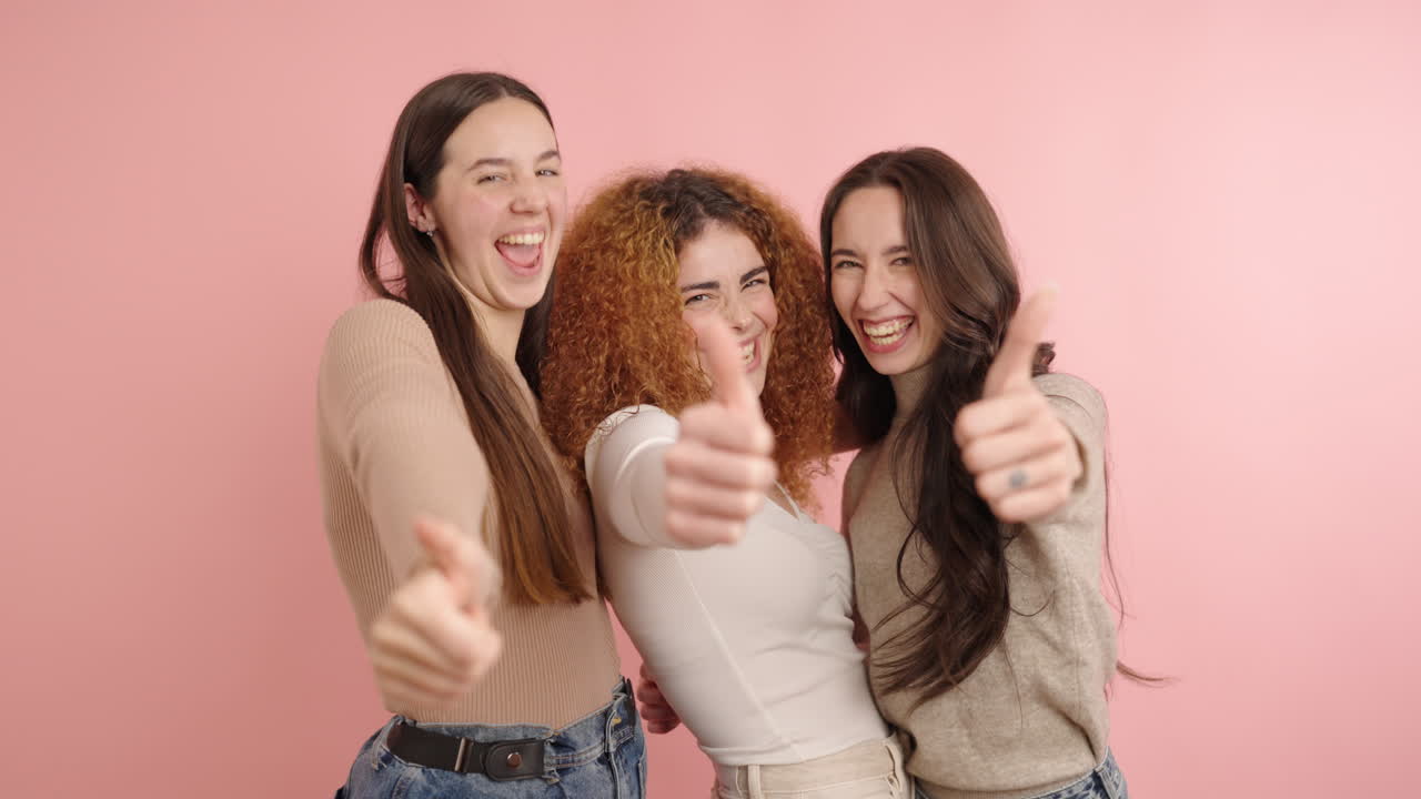 Cheerful women showing thumbs up in studio