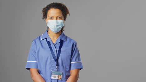 studio portrait of female nurse wearing uniform and face mask