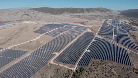 drones sobre enormes parques de energía solar fotovoltaica paneles de fila de la granja colinas día soleado