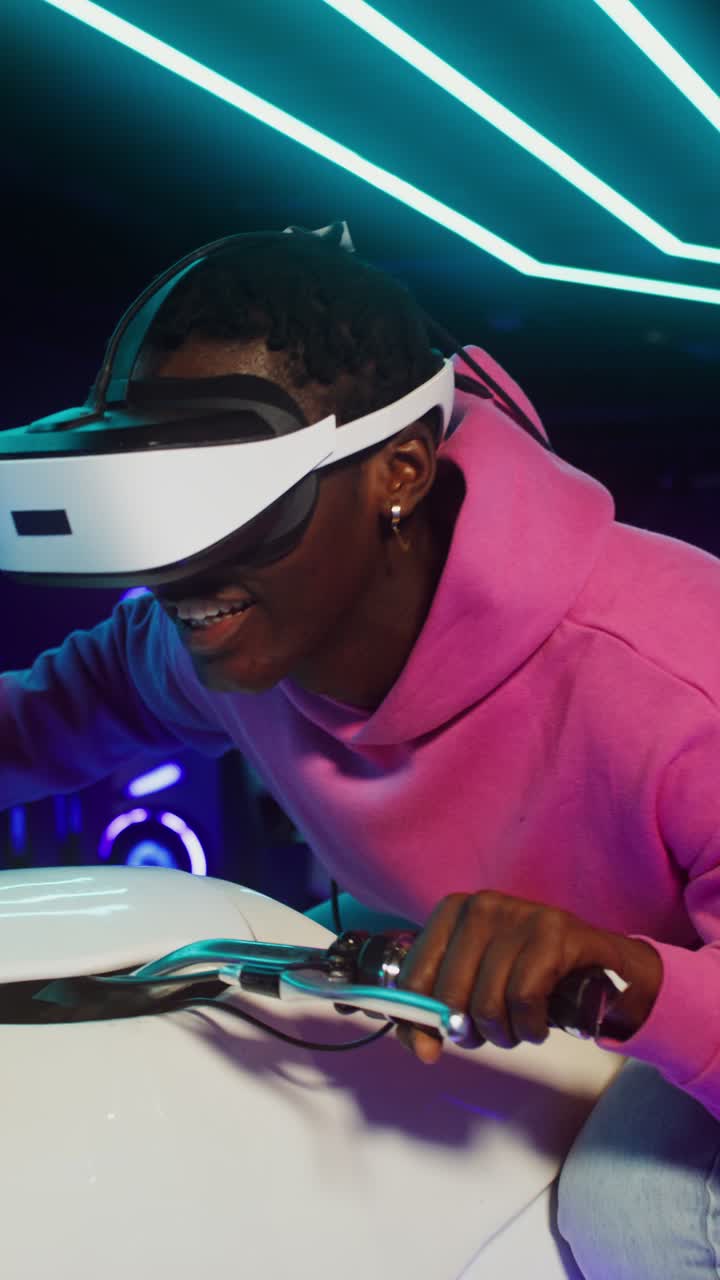 Man using VR motorcycle simulator in neon-lit arcade
