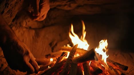 man warms his hands over a burning campfire, enjoying the flames that provide warmth and light in the surrounding darkness of a cold winter night. the cozy atmosphere invites relaxation