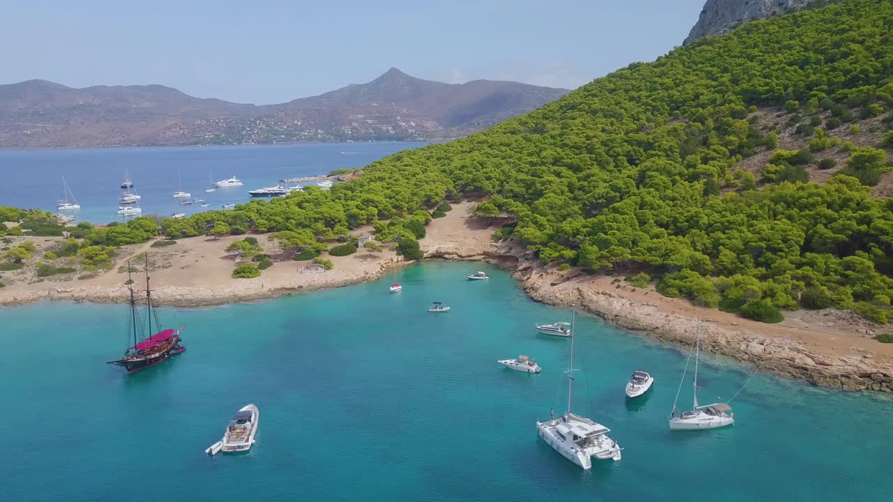 Ascending drone shot of moored yachts and catamarans on a beautiful bay for diving