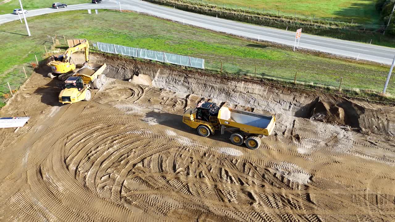 Drone captures excavator and dump truck at work on a sunny day in Cromwell, showcasing earthmoving activities