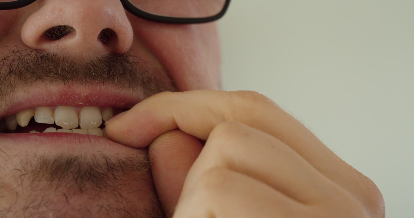 Close-up of a man biting his fingernails. Concept of stress, anxiety and nervous behavior.