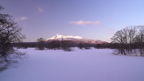 slow pan across beautiful frozen lake and alpine glow mountain at onuma koen in hokkaido