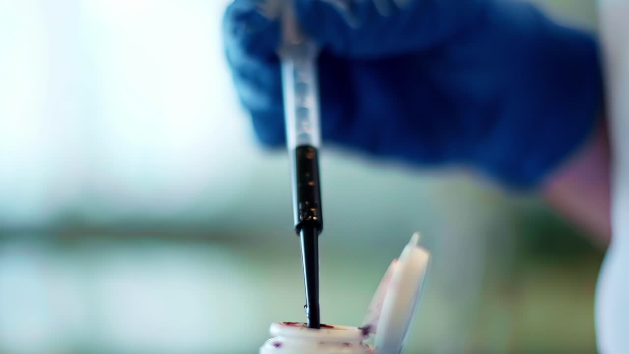 Gloved hands using pipette to draw dark liquid in sterile lab, closeup view of action