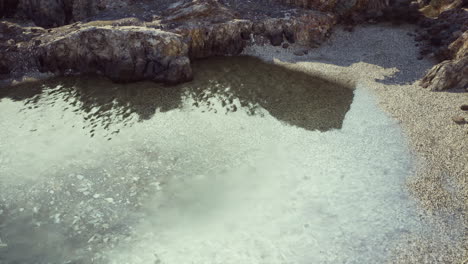 piscina clara de agua en una playa rocosa