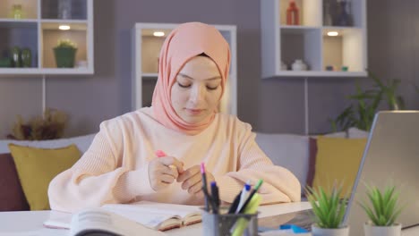 female muslim student studying using laptop and books.