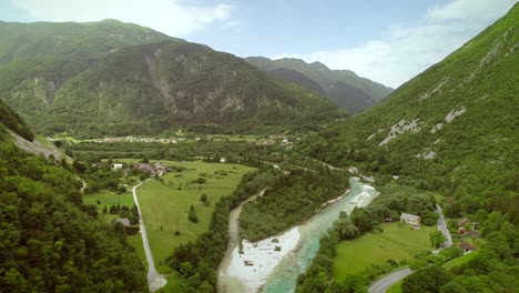 aerial view of soca river surrounded by a small town and many hills in slovenia.