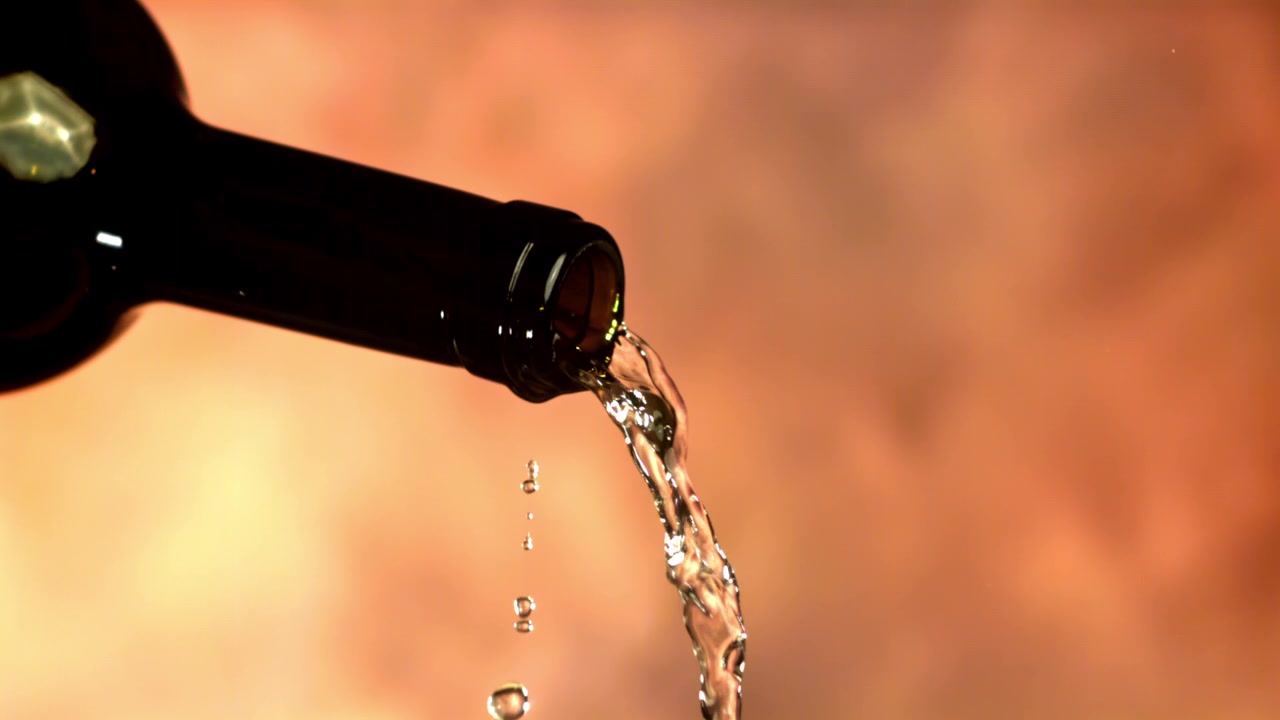 Vino bianco versato da una bottiglia scura al rallentatore