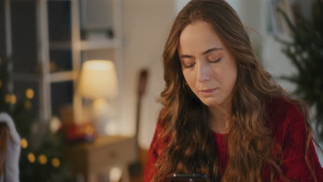 mujer usando teléfono móvil mientras está sentada en casa