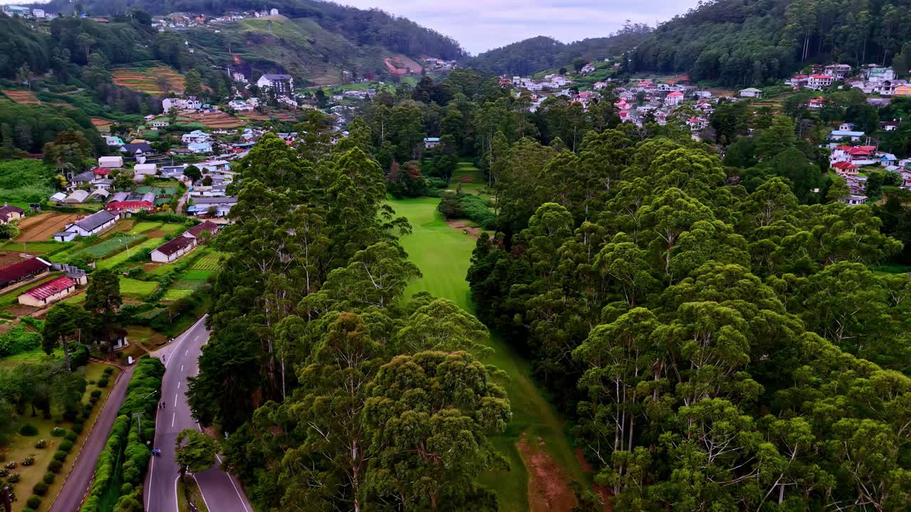 Quang cảnh từ trên cao b��ng drone của thị trấn Nuwara Eliya với những ngôi nhà được bao quanh bởi cây xanh tươi tốt, đường xá và một khu công viên xanh mướt.