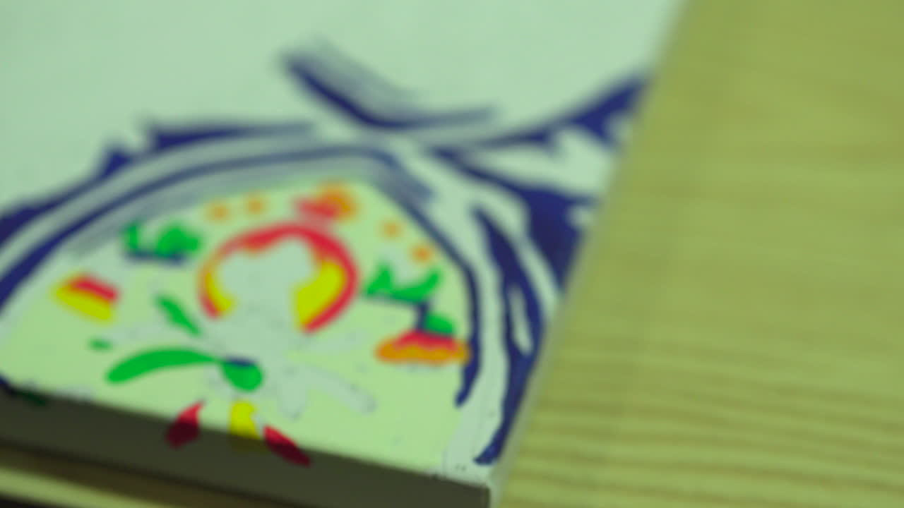 mano femenina sosteniendo un pincel mientras pinta en un lienzo colorido