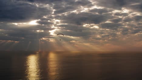 paraglider flies over ocean with beautiful golden sunset with sun rays. inspiration and motivation concept.