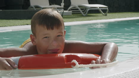 Today-he-is-too-lazy-to-swim-Relaxed-boy-floating-on-safety-ring-in-the-pool