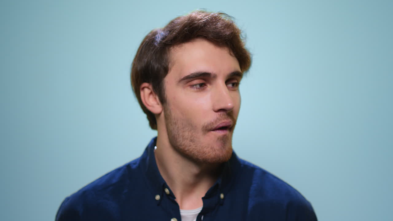 Smiling man chewing gum in studio. Handsome guy blowing bubble on camera