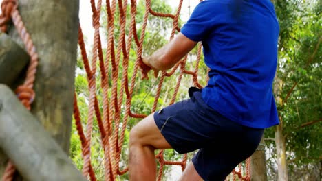 hombre en forma subiendo una red durante el curso de obstáculos 4k