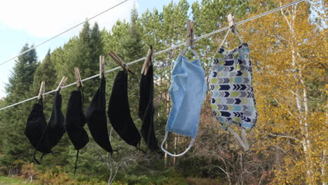 anti virus face masks hanging on a clothesline in front of an autum forest background