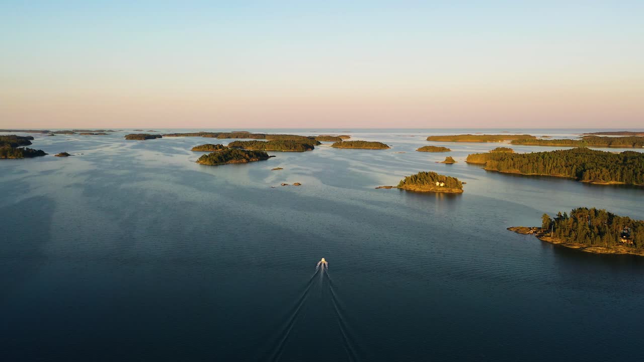 Aerial view following a boat, driving between islands, tranquil, summer evening, at the Gulf of Finland, in the Finnish archipelago- rising, drone shot