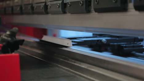 factory worker using industrial bending machine for aluminium plate to manufacture an angled plaque