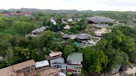 tropical exotic resort villa complex on bali coastline, aerial drone fly backward view