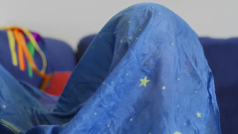 bebé sonriendo y riendo jugando con una seda azul con estrellas amarillas en cámara lenta