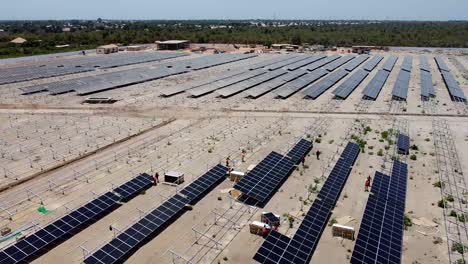 vista aérea de los técnicos e ingenieros que trabajan instalando paneles solares bifaciales en el sitio del proyecto solar fotovoltaico de jambur en construcción en gambia, áfrica occidental