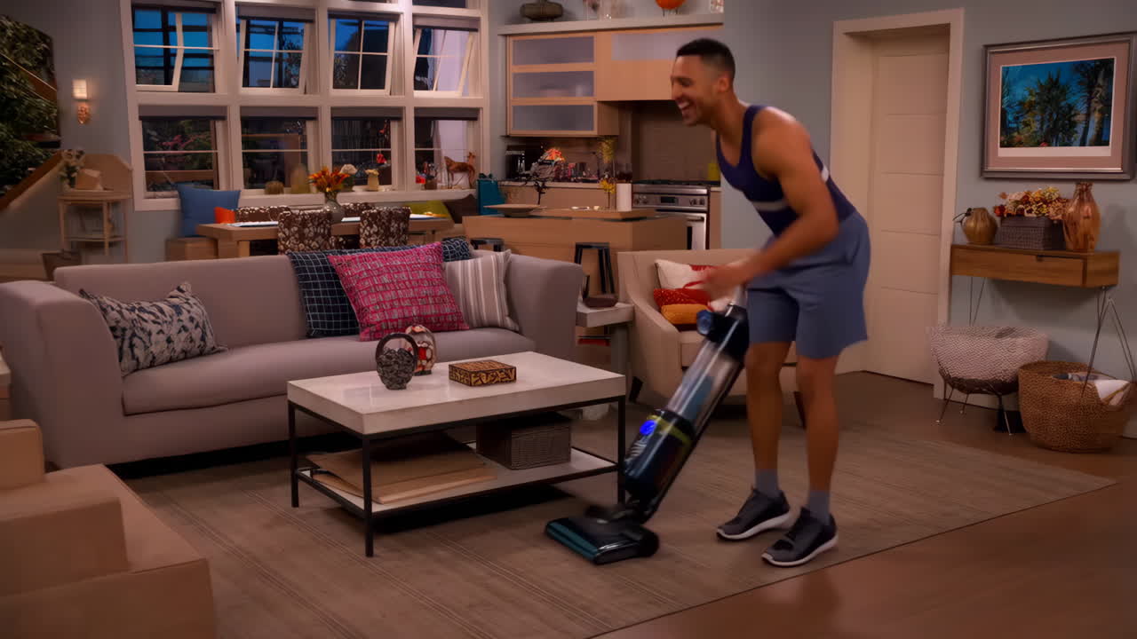 A man enthusiastically vacuums his modern living room