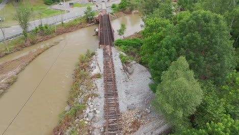 aerial drone view: damaged and eroded train tracks adjacent to river in flood-stricken vermont