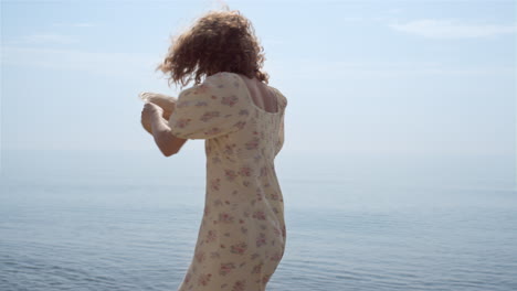 Laughing-woman-spinning-playing-with-straw-hat-on-beach.-Girl-walking-on-waves.