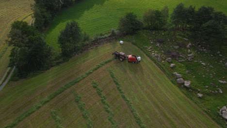 tractor con máquina empacadora haciendo pacas de ensilaje en tierras de cultivo, tiro ascendente