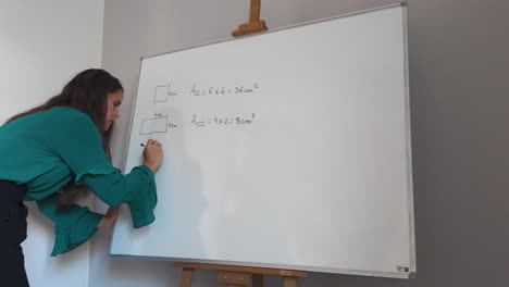 Woman teaches geometry formulas on a whiteboard in a classroom setting