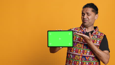 man shows thumbs down sign gesturing regarding mockup device, studio background