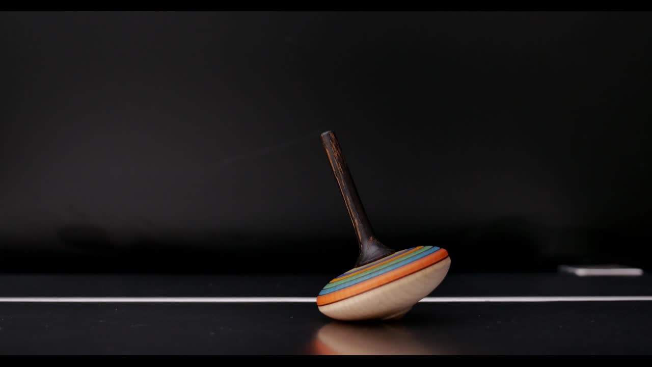 A hand spins the spinning top, it rotates a couple of times and stops
