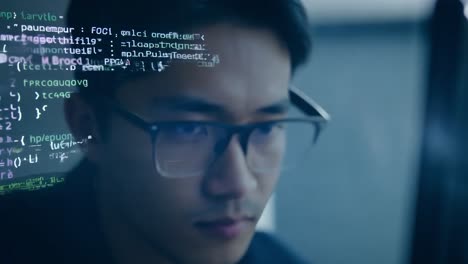 young asian developer concentrating on code, with reflections visible in his glasses, showcases a focused work environment