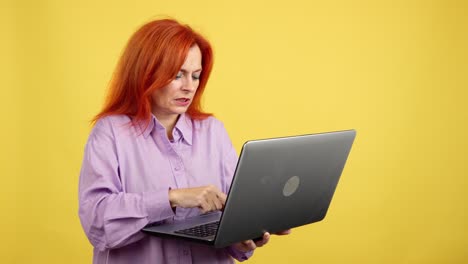 red-haired woman interacting with laptop on yellow background