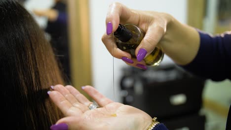 slow motion of golden hair oil being laid in hand